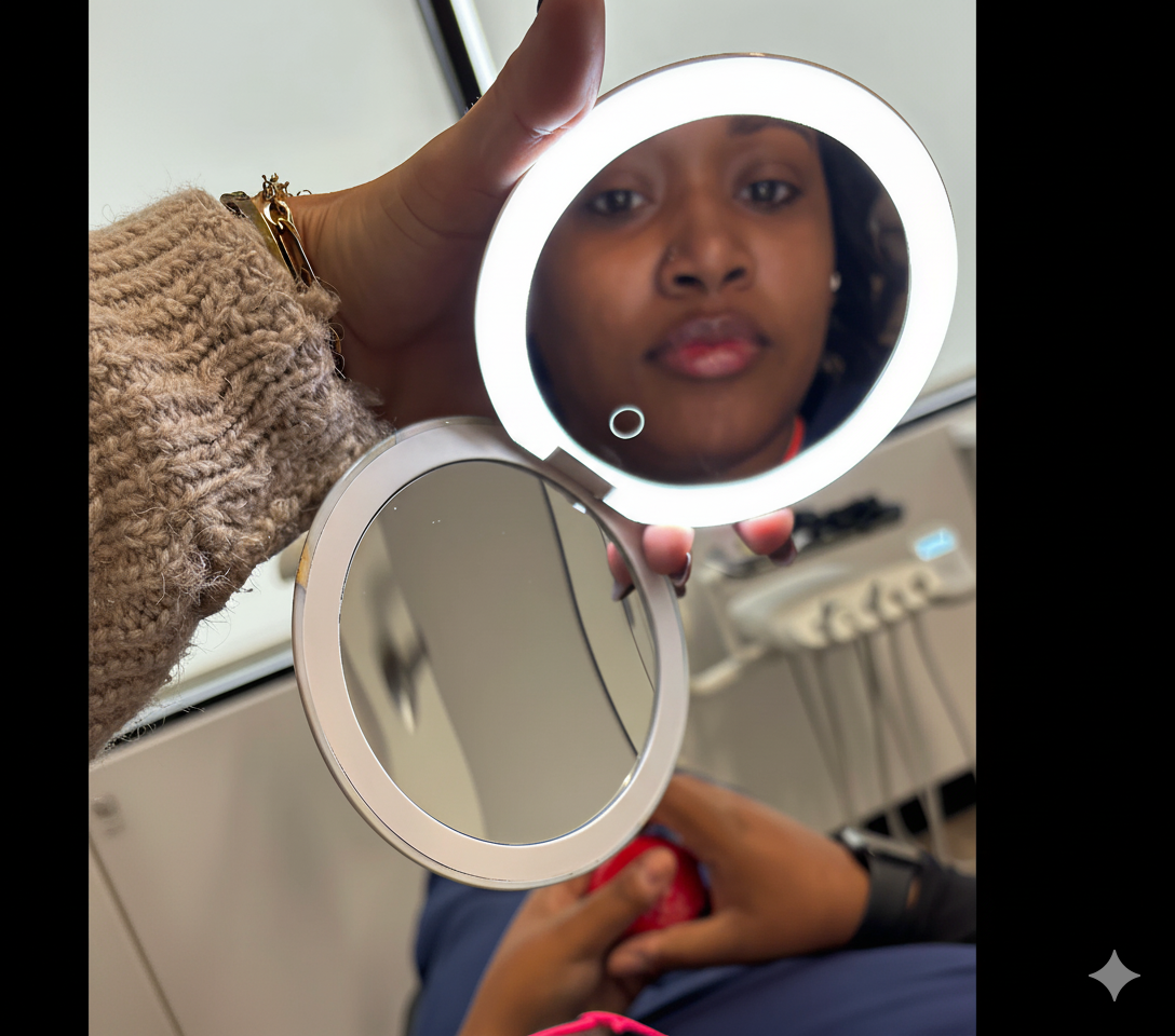 An illuminated compact mirror held by a hand reflects a woman's face.