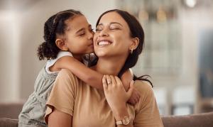 A young girl kisses a smiling woman's cheek.