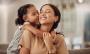 a little girl is kissing her mother on the cheek while sitting on a couch .