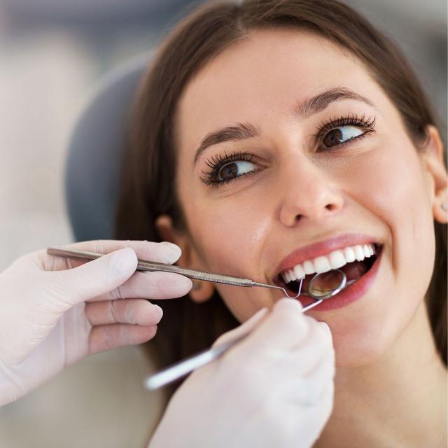 A woman smiles widely during a dental examination.
