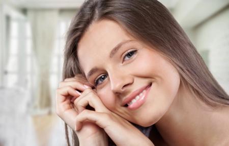 a close up of a woman smiling with her hand on her face .