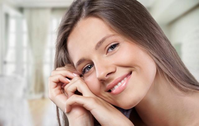 a close up of a woman smiling with her hand on her face .