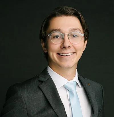 a man with a beard is wearing a blue scrub top and smiling for the camera .