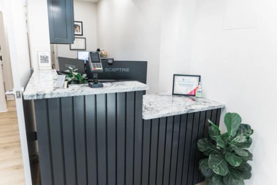 a reception desk in a dental office with a plant in front of it .