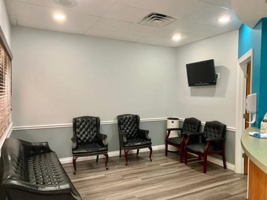 a waiting room with a couch , chairs , and a flat screen tv .