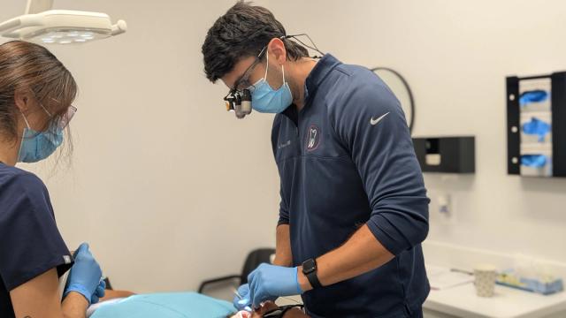 a dentist is examining a patient 's teeth in a dental office .