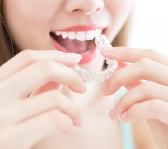 a woman is holding a clear brace in her mouth .