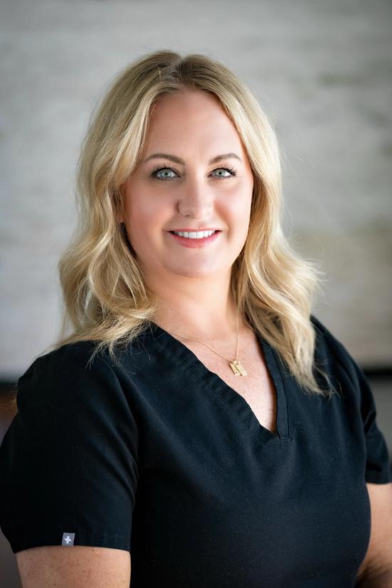 a woman wearing a black scrub top is smiling for the camera