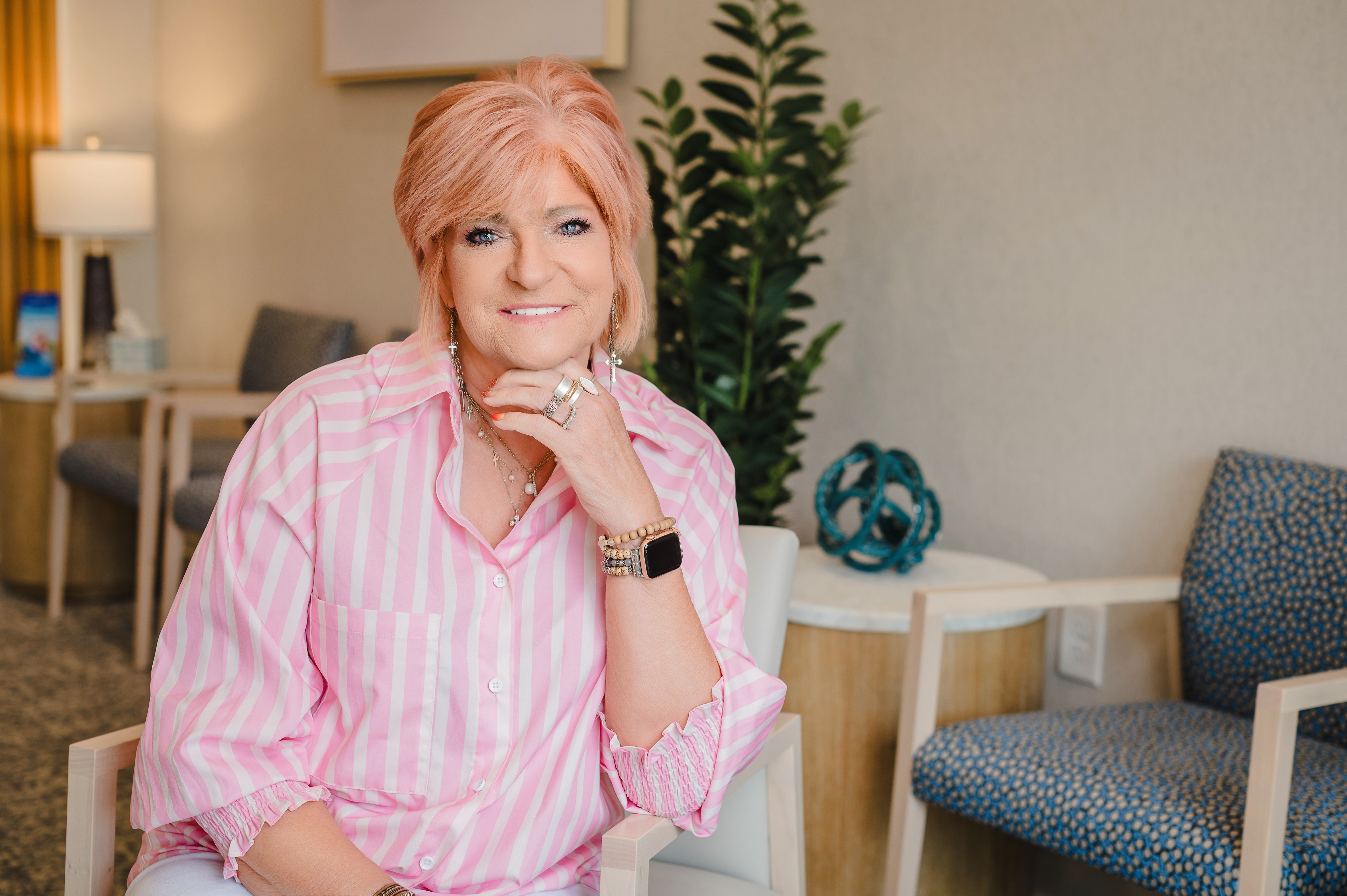 a woman in a pink striped shirt is sitting in a chair in a waiting room .
