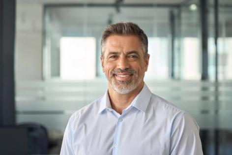 a man with a beard is smiling for the camera in an office .