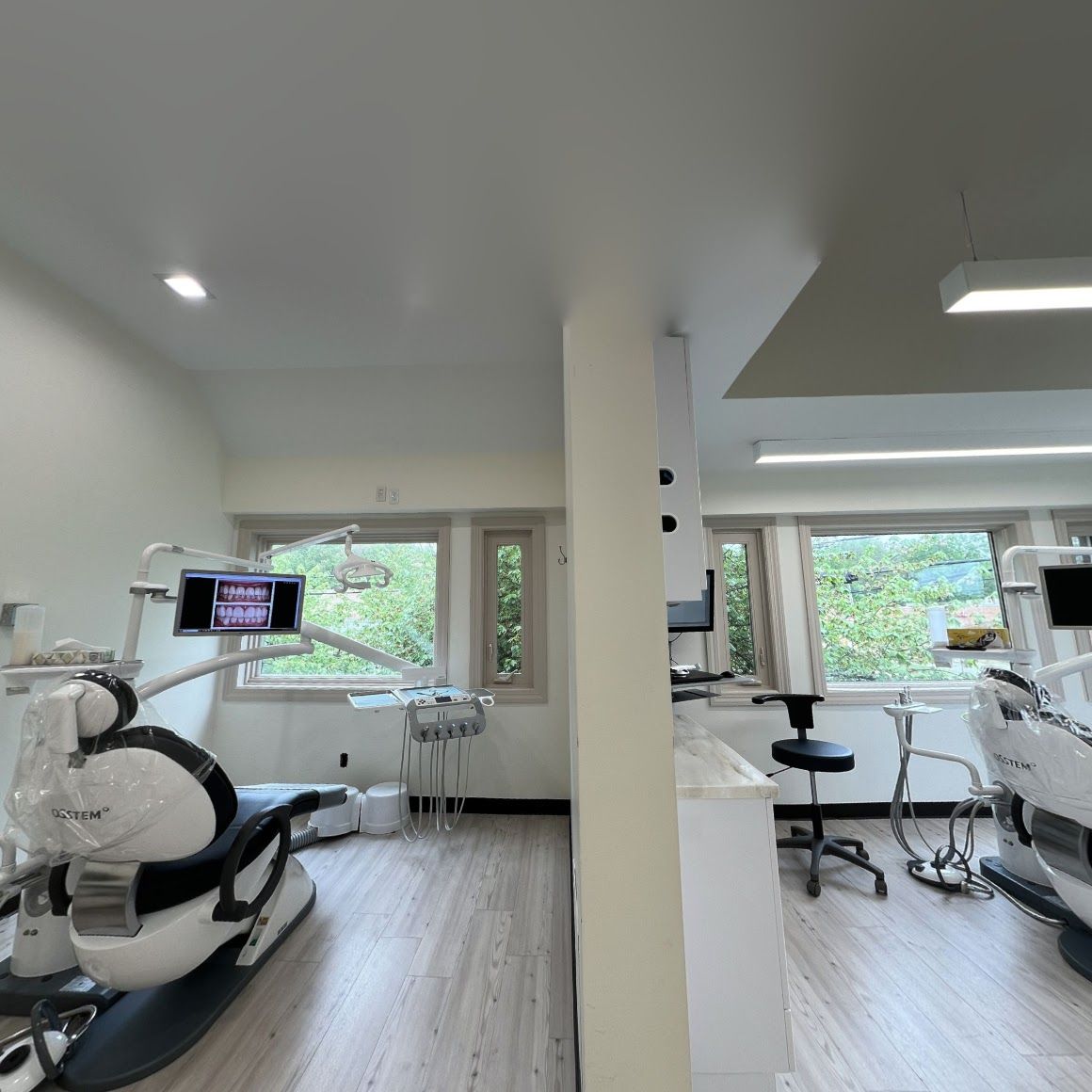 a dental office with two dental chairs and a monitor on the wall .