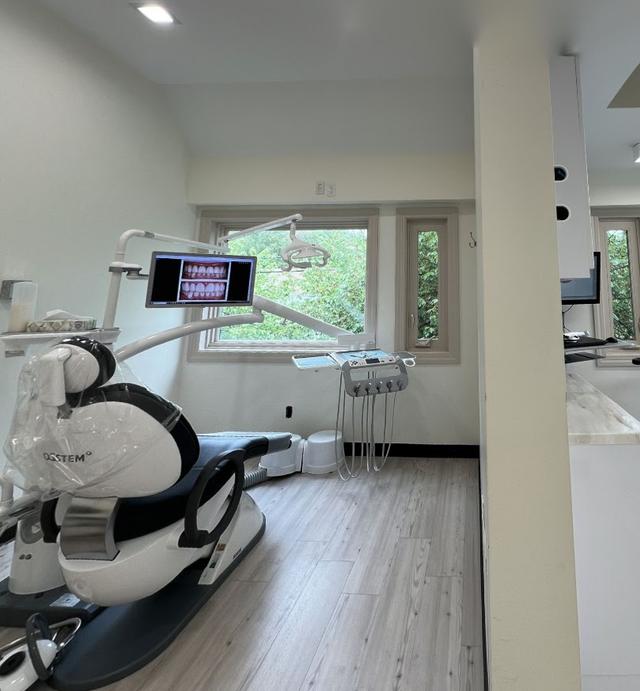 a dental office with two dental chairs and a monitor on the wall .