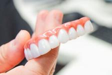 a person is holding a denture in their hand .