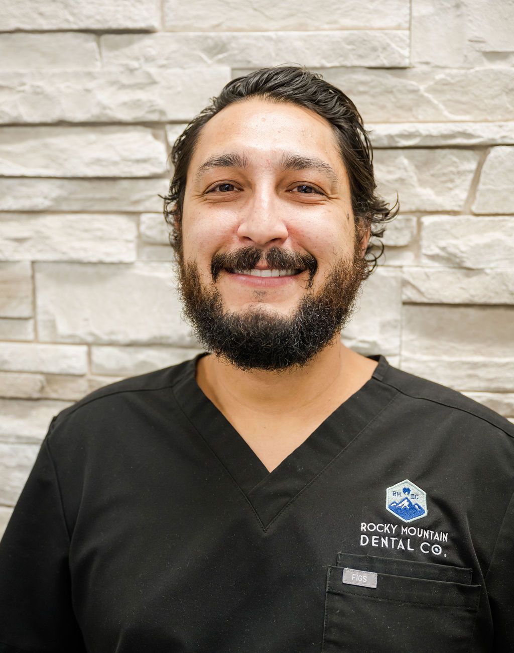 a man with a beard is wearing a rocky mountain dental co. scrub