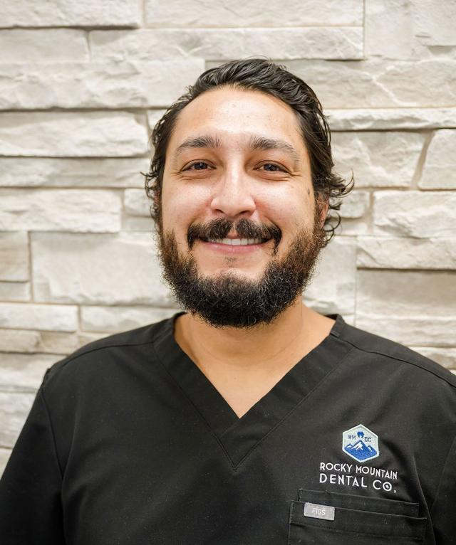 a man with a beard is wearing a rocky mountain dental co. scrub