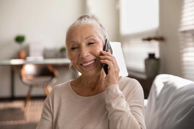 an elderly woman is smiling while talking on a cell phone .