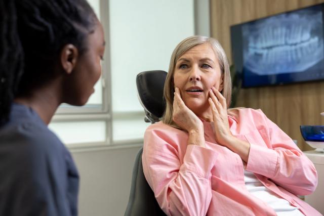 a woman is sitting in a dental chair talking to a dentist .