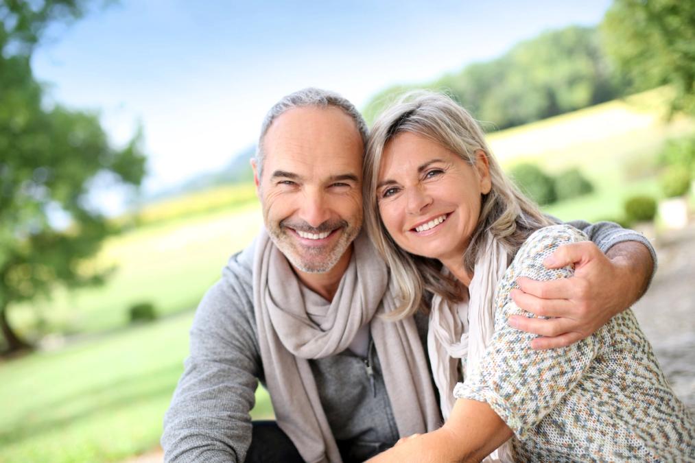 Smiling middle-aged couple embracing outdoors.