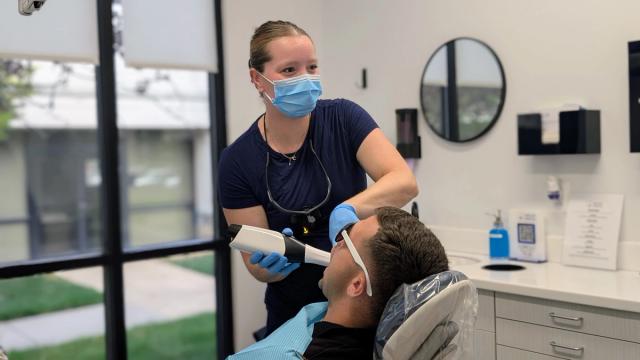 a woman is taking a picture of a man 's teeth in a dental office .