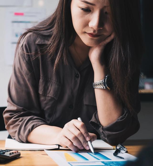 a woman is sitting at a desk writing in a notebook .