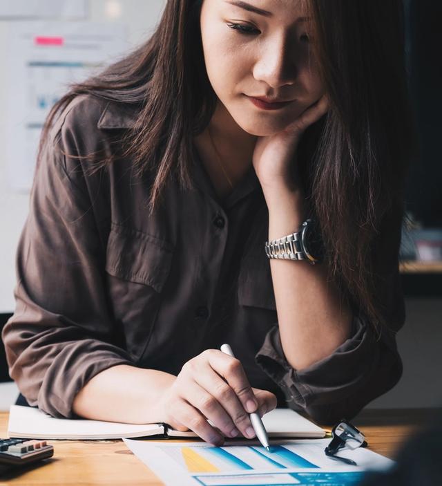 a woman is sitting at a desk writing in a notebook .