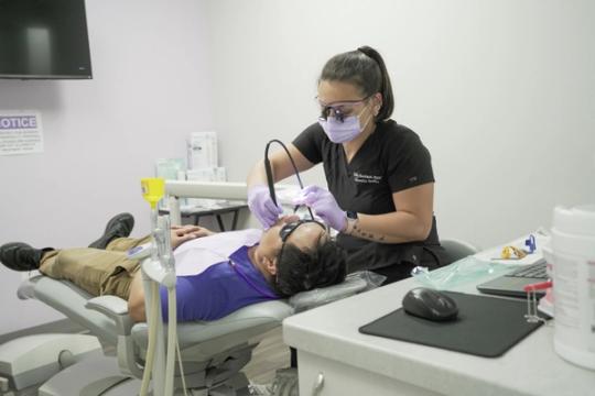 a woman is examining a man 's teeth in a dental office .