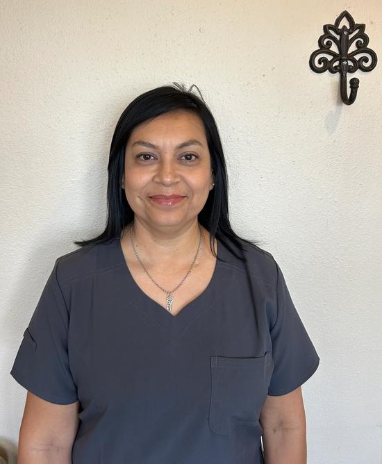 a woman in a grey scrub top is smiling for the camera