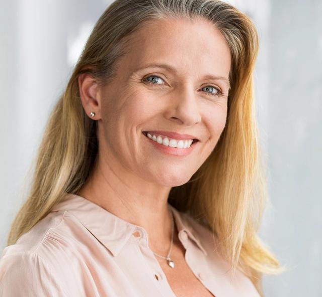 a woman with long blonde hair is smiling for the camera .