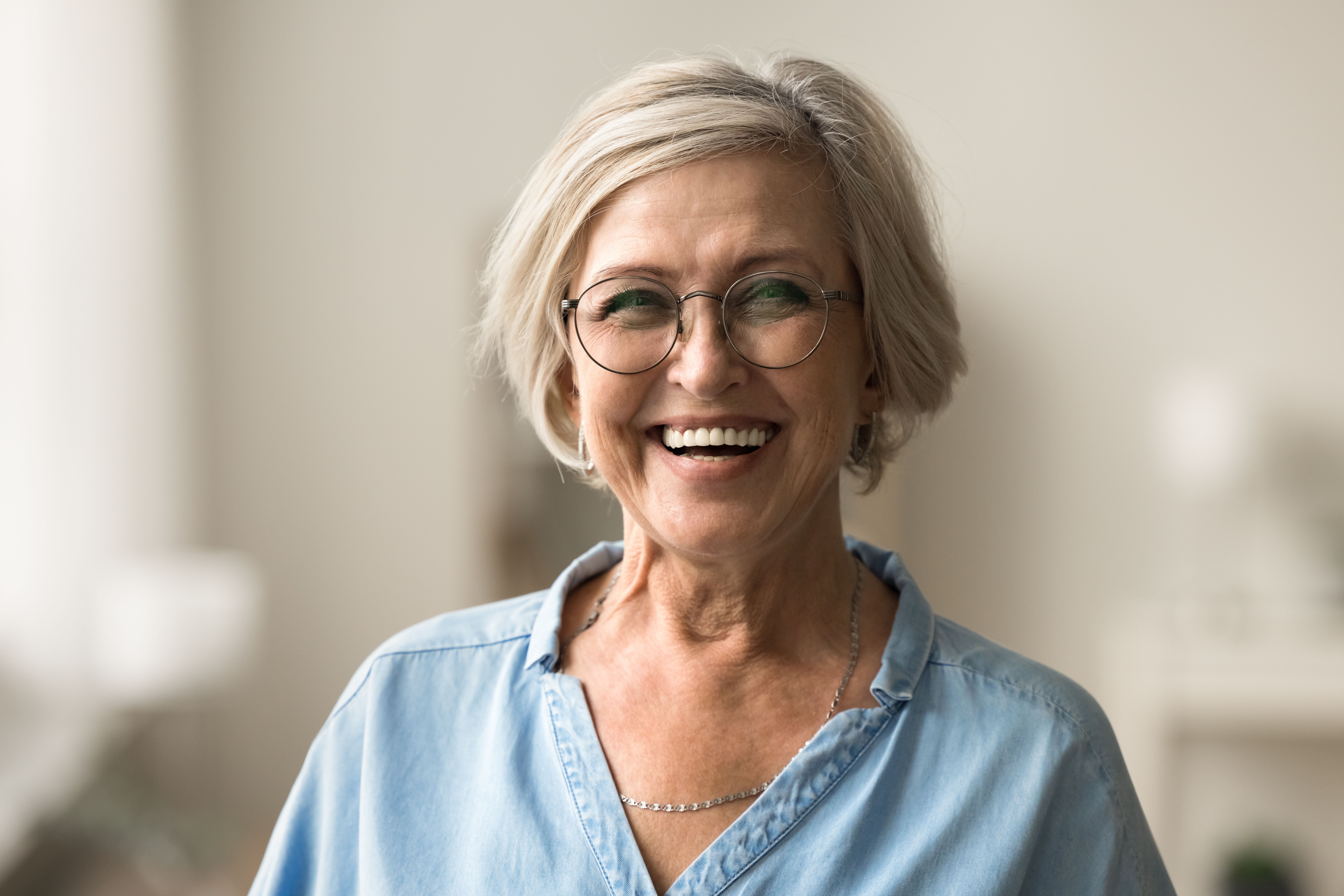 an older woman wearing glasses and a blue shirt is smiling for the camera .