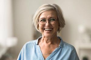 an older woman wearing glasses and a blue shirt is smiling for the camera .