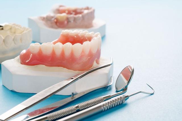 a pair of dentures and dental instruments on a blue surface .
