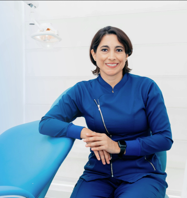 a woman in a blue uniform sits in a dental chair