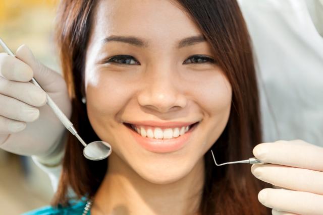 a woman is smiling while having her teeth examined by a dentist .