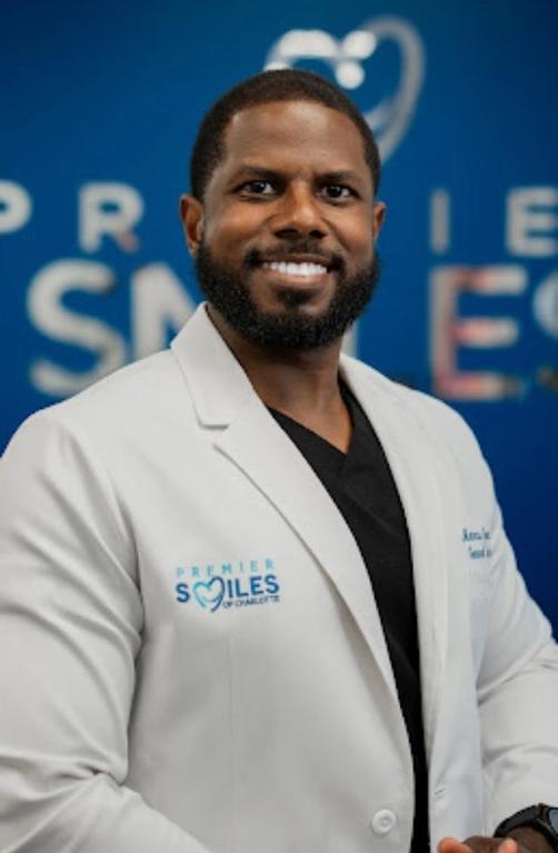 a man wearing a white lab coat that says premier smiles on it