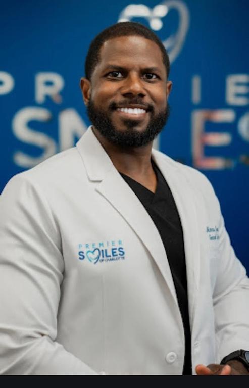 a man wearing a white lab coat that says premier smiles on it