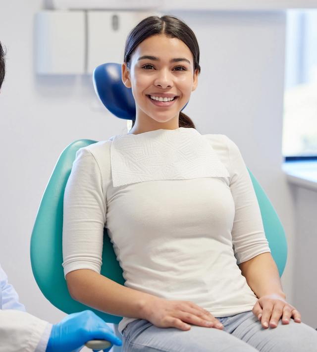 a woman is sitting in a dental chair next to a dentist .