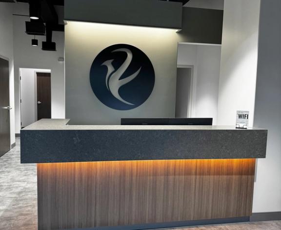 Modern reception desk with under-lighting and a circular logo on the wall.