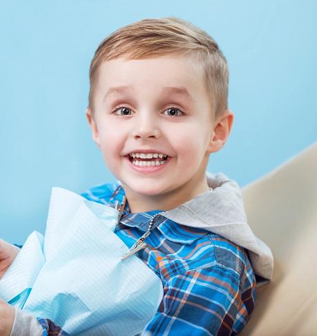 a young boy is sitting in a dental chair holding a model of his teeth .