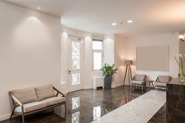 a waiting room with a couch , chairs , and a lamp .