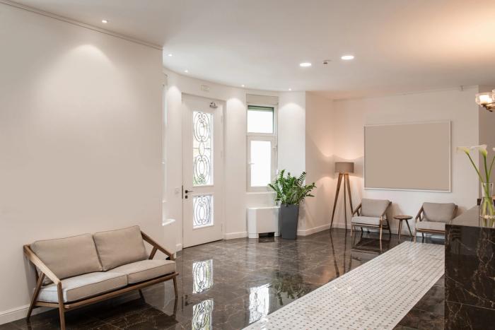 a waiting room with a couch , chairs , and a lamp .