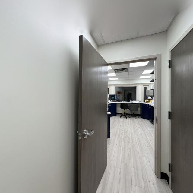 a hallway with a door open leading to a room with a desk and chairs .