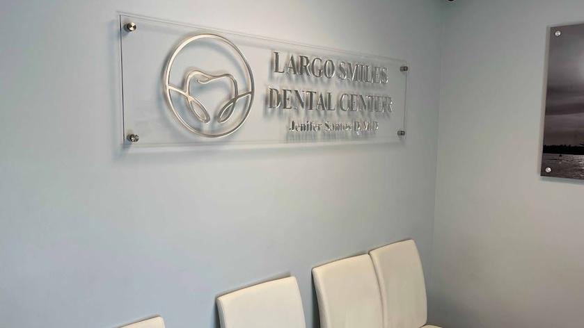 a dental center waiting room with a sign on the wall and chairs .
