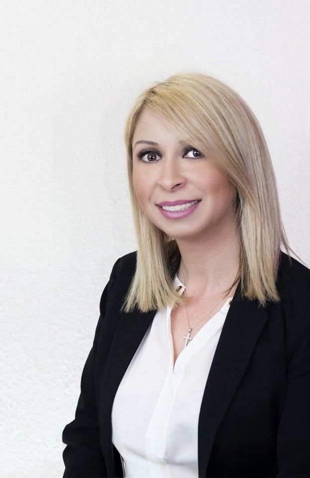 a woman wearing a white shirt and a black jacket smiles for the camera