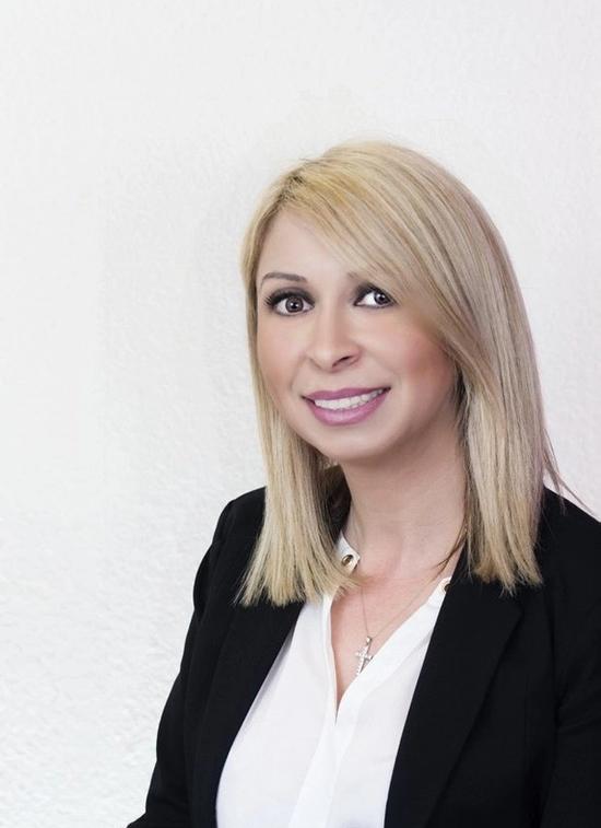 a woman wearing a white shirt and a black jacket smiles for the camera