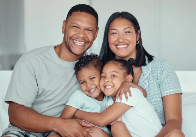 a family is sitting on a couch and smiling for the camera .