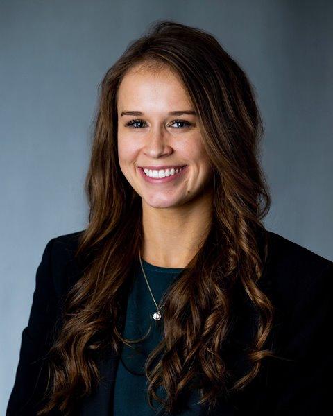 a woman with long brown hair and a necklace is smiling for the camera .