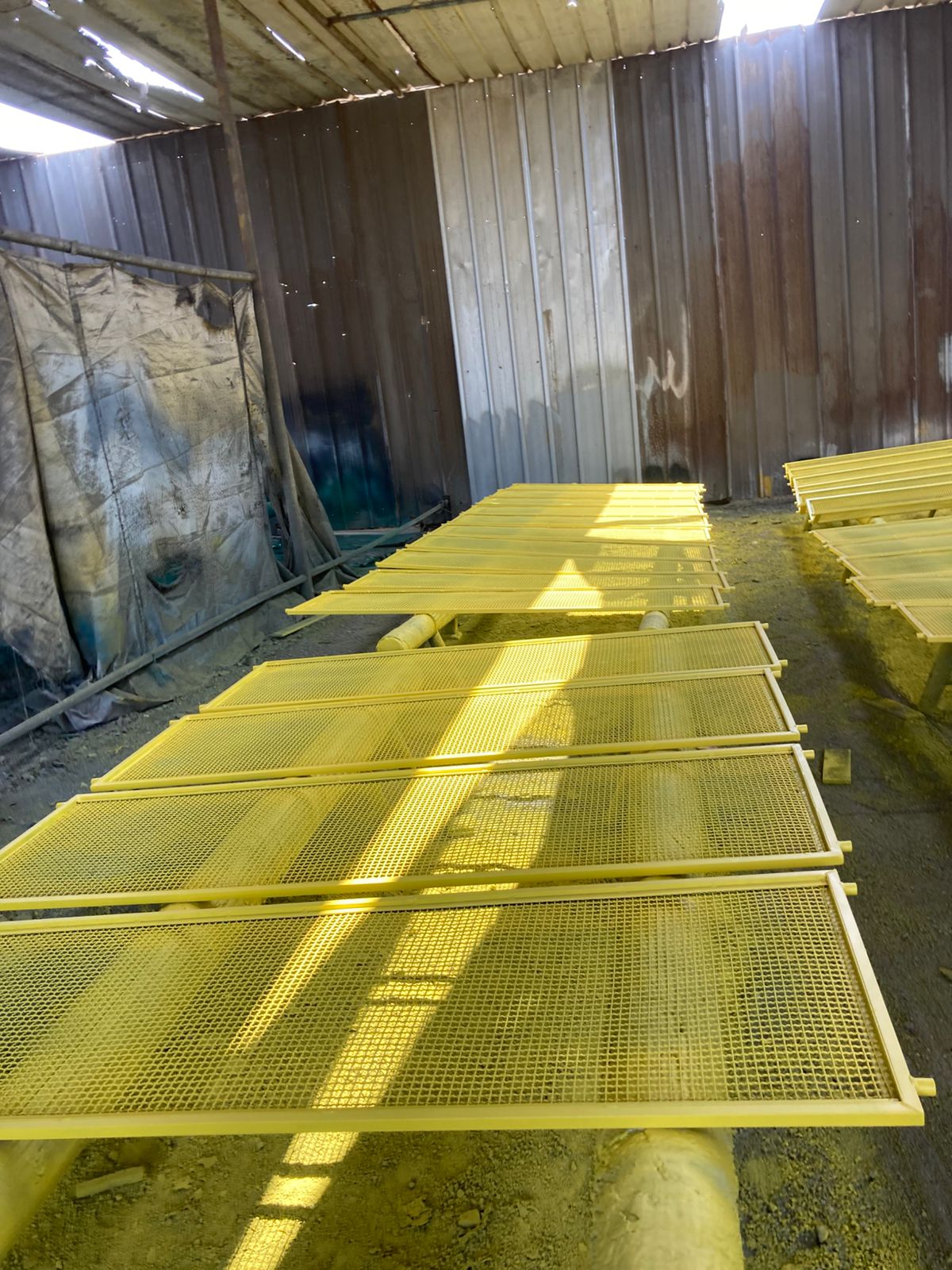 Paneles de malla vibratoria para equipos mineros, recién pintados de amarillo en el taller