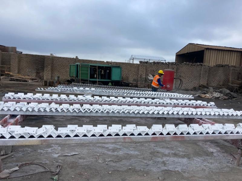 Segmentos curvos de acero con acabado blanco en el patio de obra, con la cuadrilla trabajando