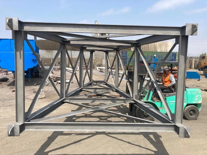Estructura reticular de acero de gran tamaño con imprimación, junto a un montacargas