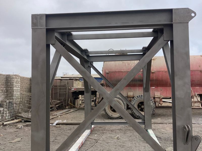 Torre de acero arriostrada con imprimación, junto a un tanque de almacenamiento